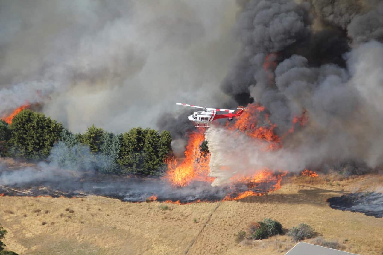 Helicopter dropping water on a huge blaze.