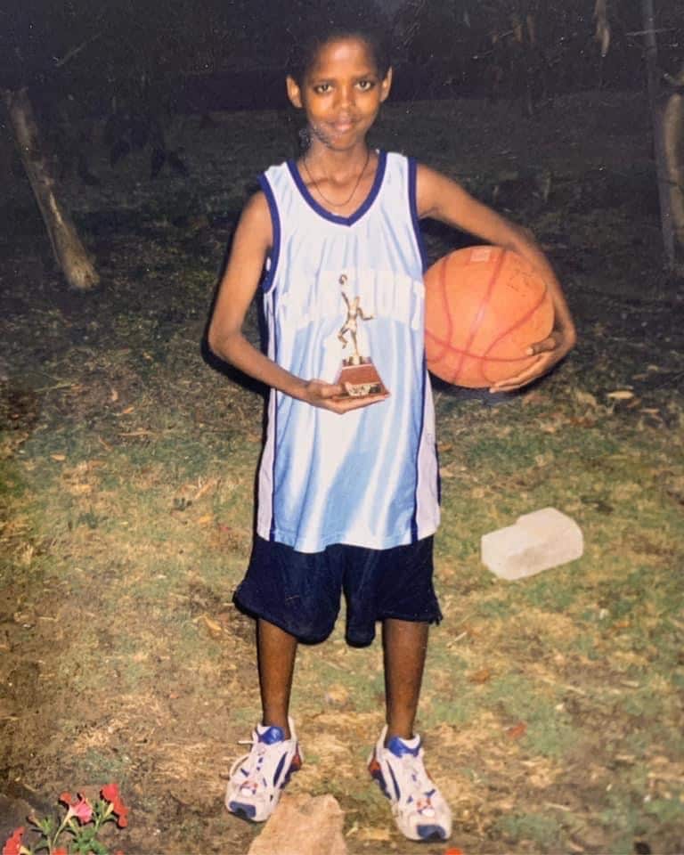 Joe White as a 13-year-old boy, holding a basketball on his side and a trophy in front.