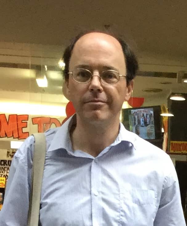 A man with round glasses in a white dress shirt