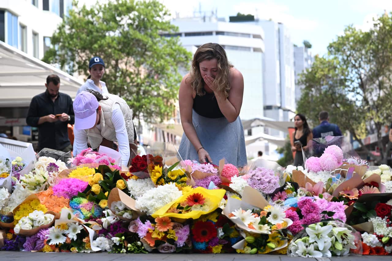 A woman cries over a spray of flowers. 