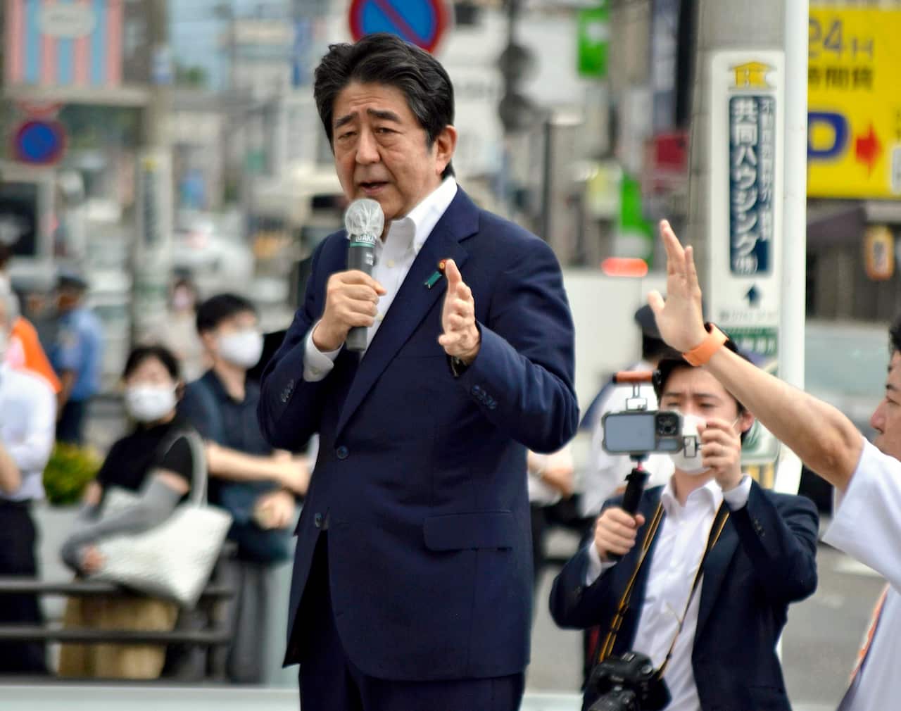 Shinzo Abe speaking into a microphone in front of a crowd