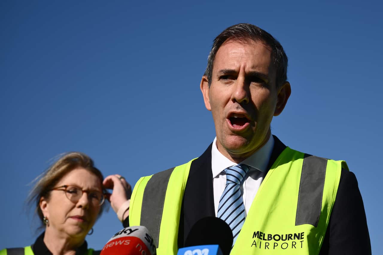Jim Chalmers wearing a high viz vest speaks to the media