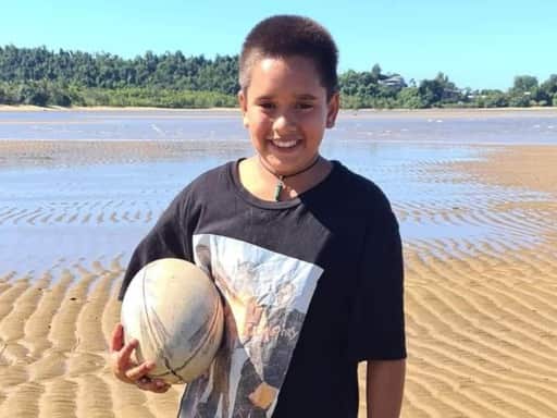 Daemarius Purcell-Appo stands on a beach holding a rugby ball