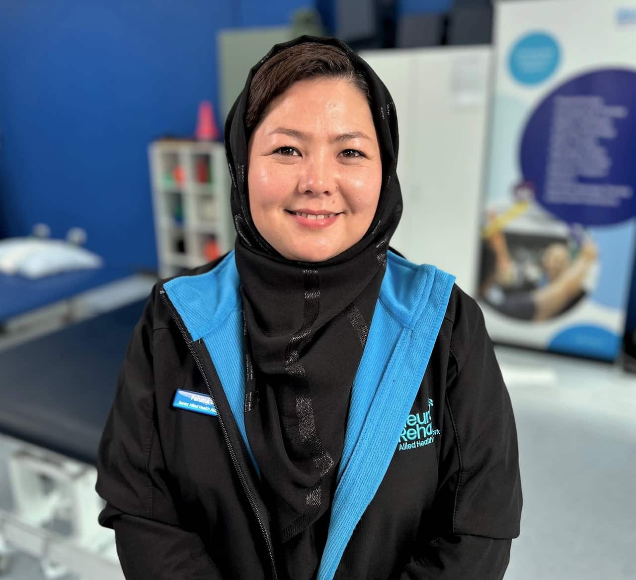 A woman in a blue and black jacket sitting in a gymnasium.