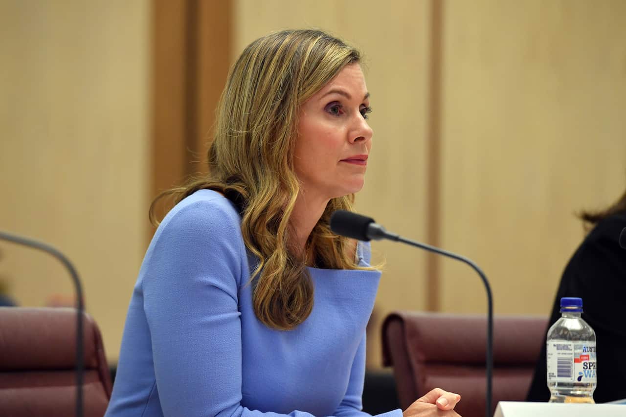 A woman seated at a desk in front of a microphone.