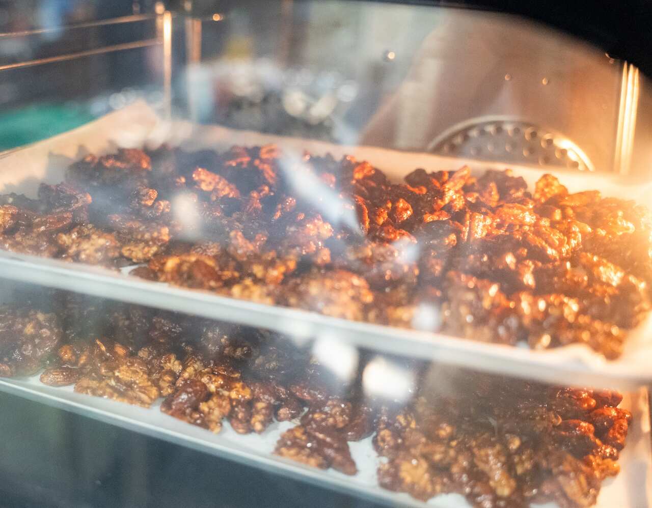 Spicy nuts seen through the glass, baking in an oven.