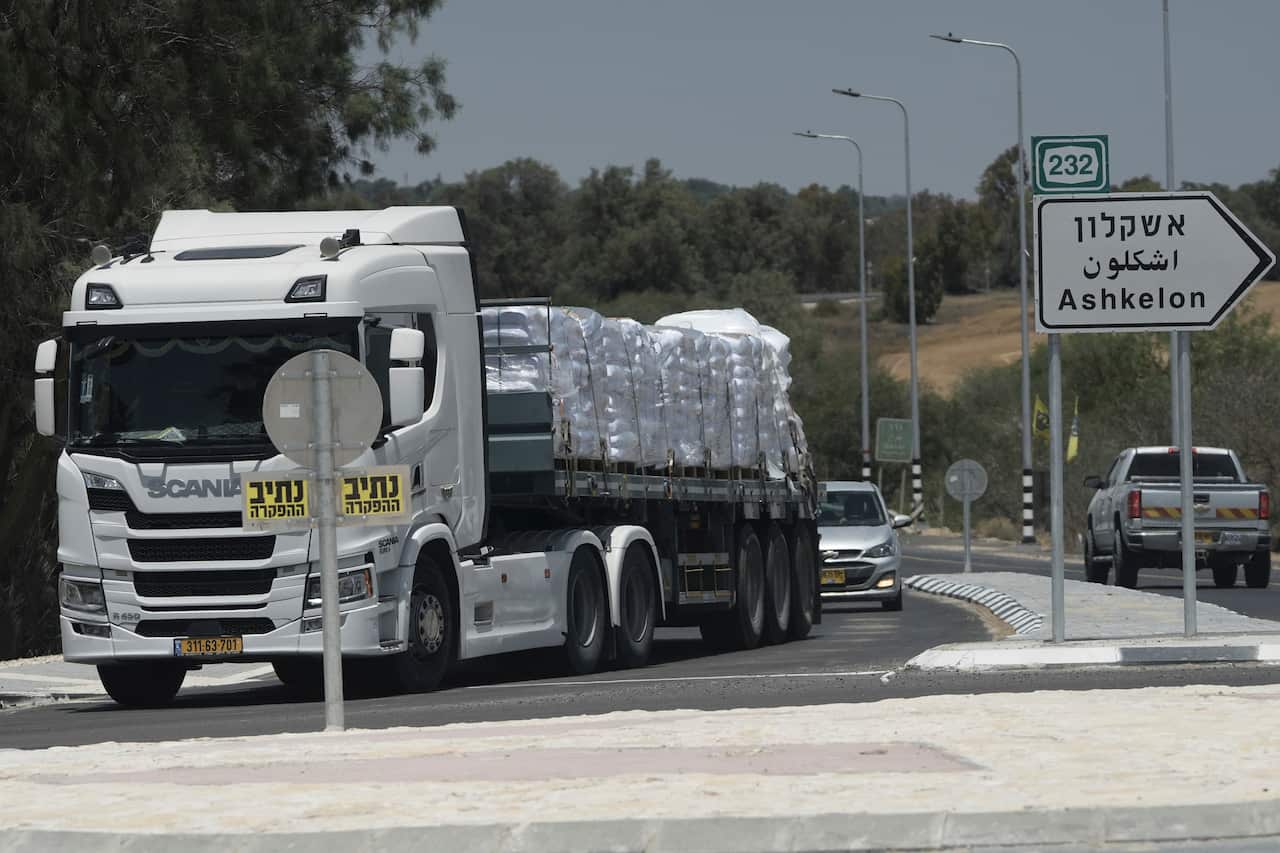 A truck loaded with bags of flour, parked next to Hebrew, English and Arabic street signs
