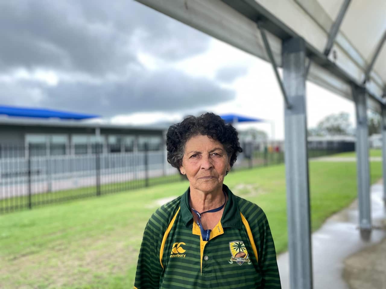 An elderly woman looks serious in a green striped jersey. 