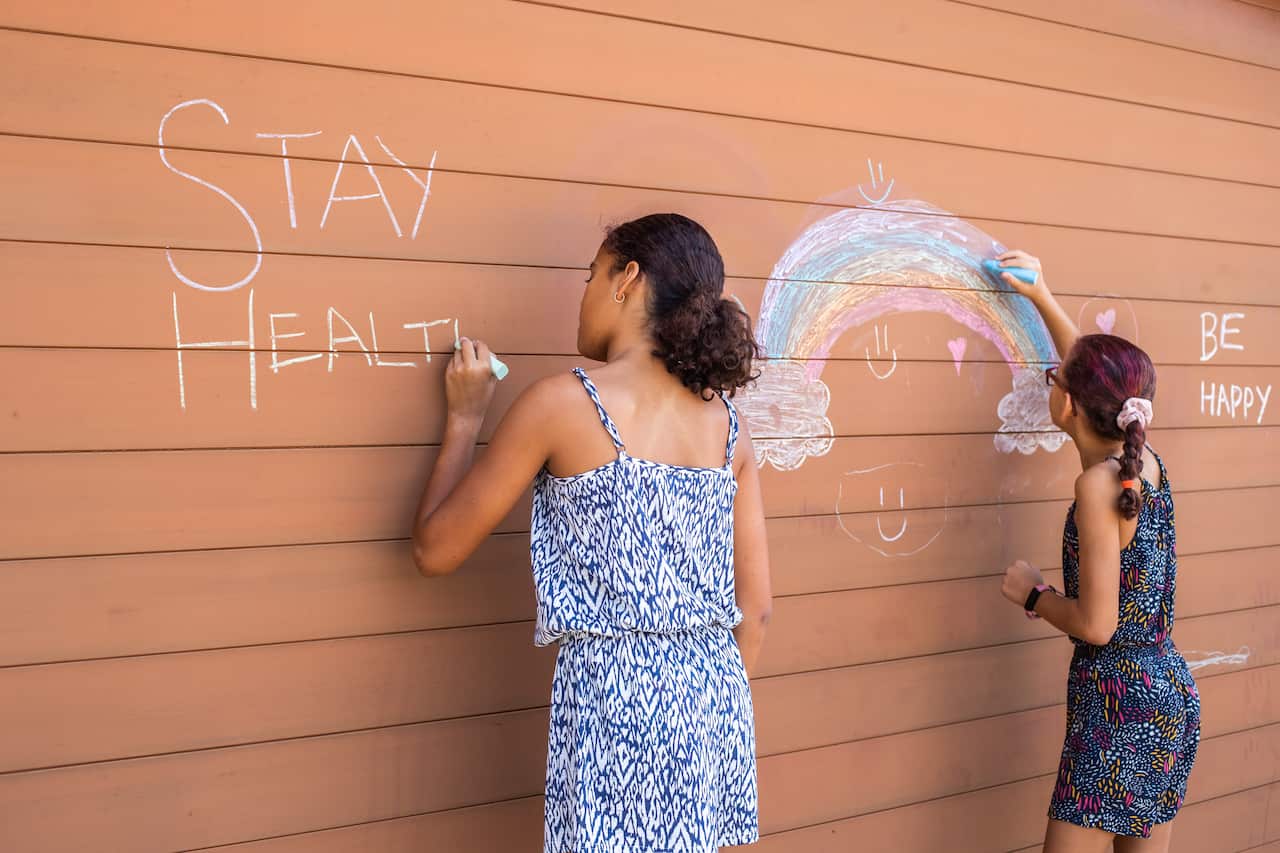 Children drawing with chalk on a garage door.