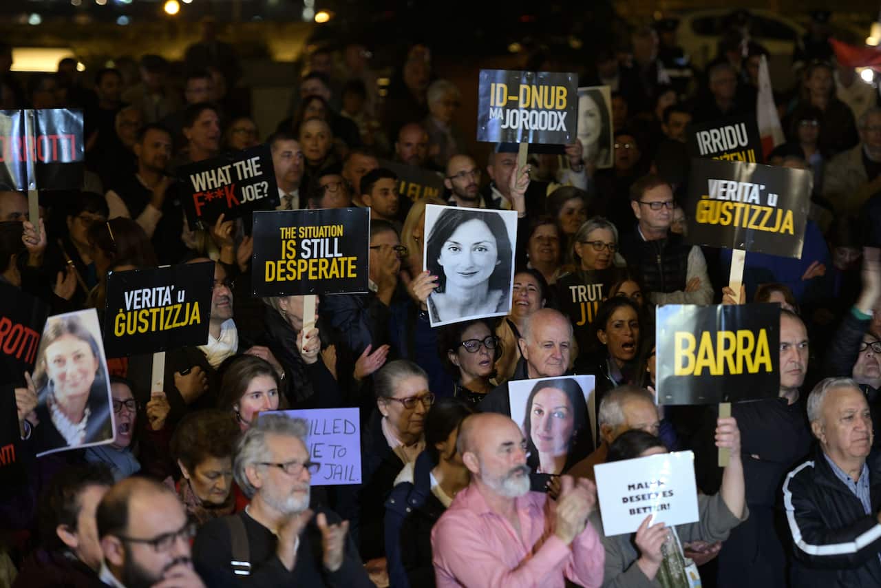 Protesters at a demonstration holding photos of journalist Daphne Caruana Galizia and placards in English and Maltese