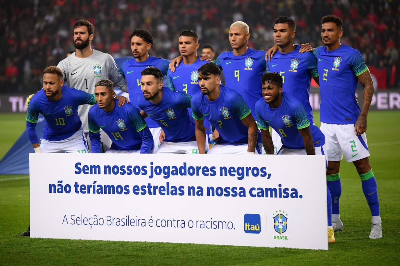 Team of blue jersey-wearing players pose with a sign
