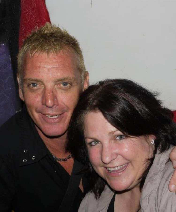 A man and a women embrace as they smile at the camera.