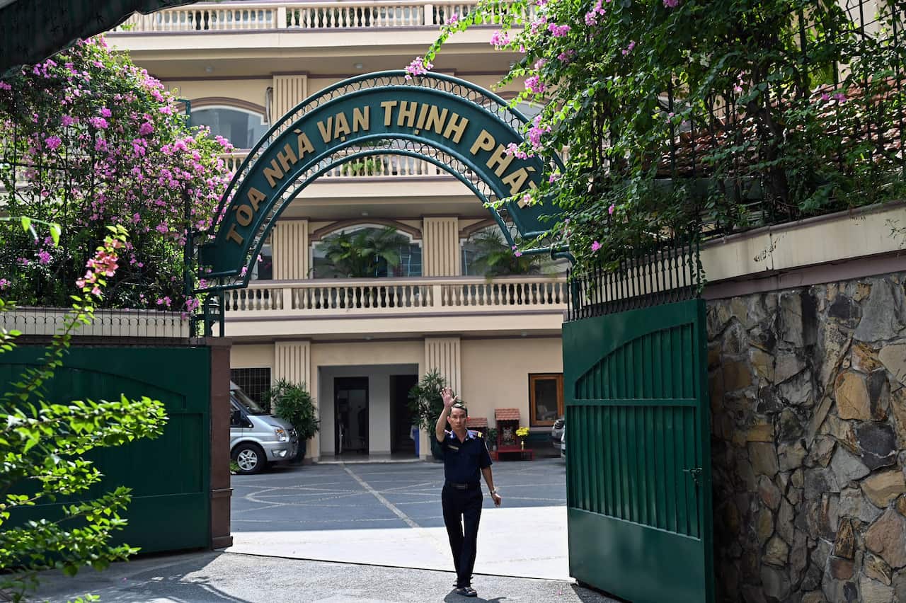A security guard waving at the gates of a building.