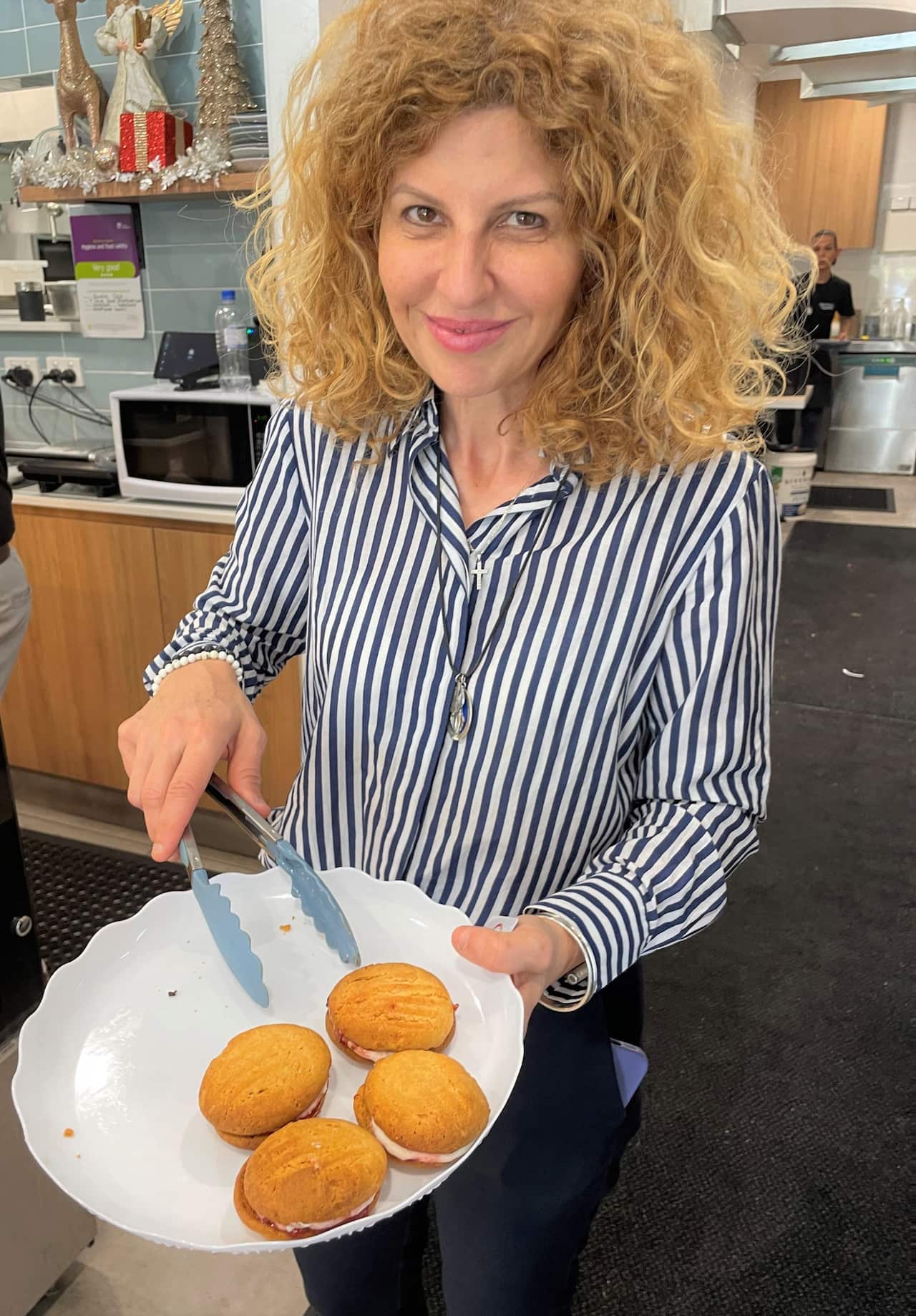 Bridget Sakr in a striped shirt holding a plate of cakes. 