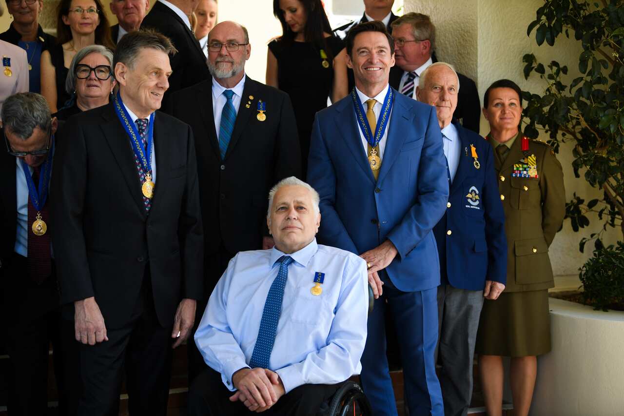 Men standing in suits after receiving an award. A man with an award is in a wheelchair 