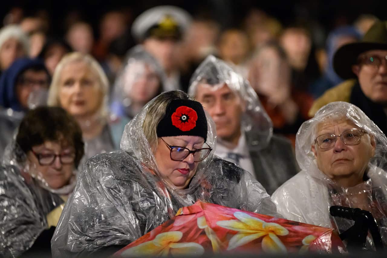 A large group of people in rain ponchos sitting down.
