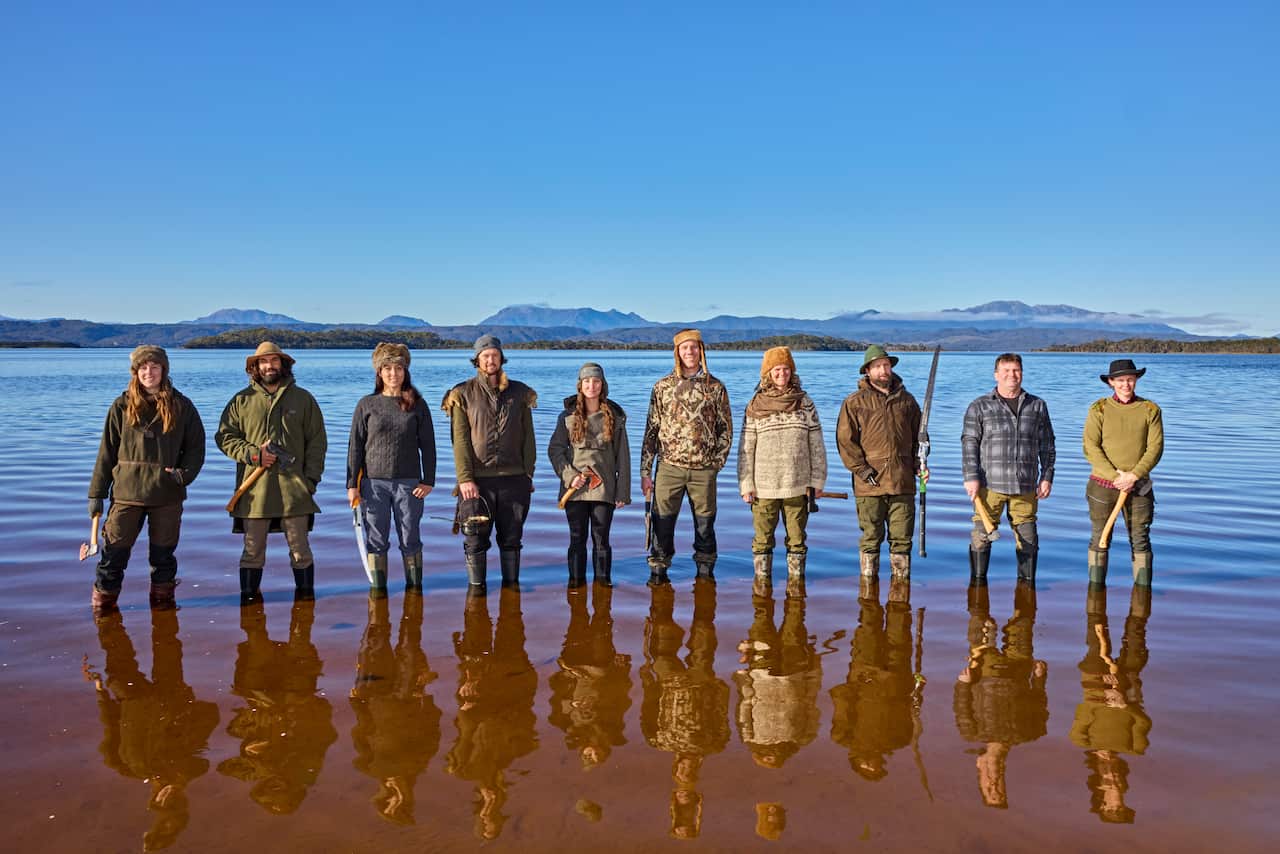 Five men and five women wearing outdoor gear standing in a creek smiling