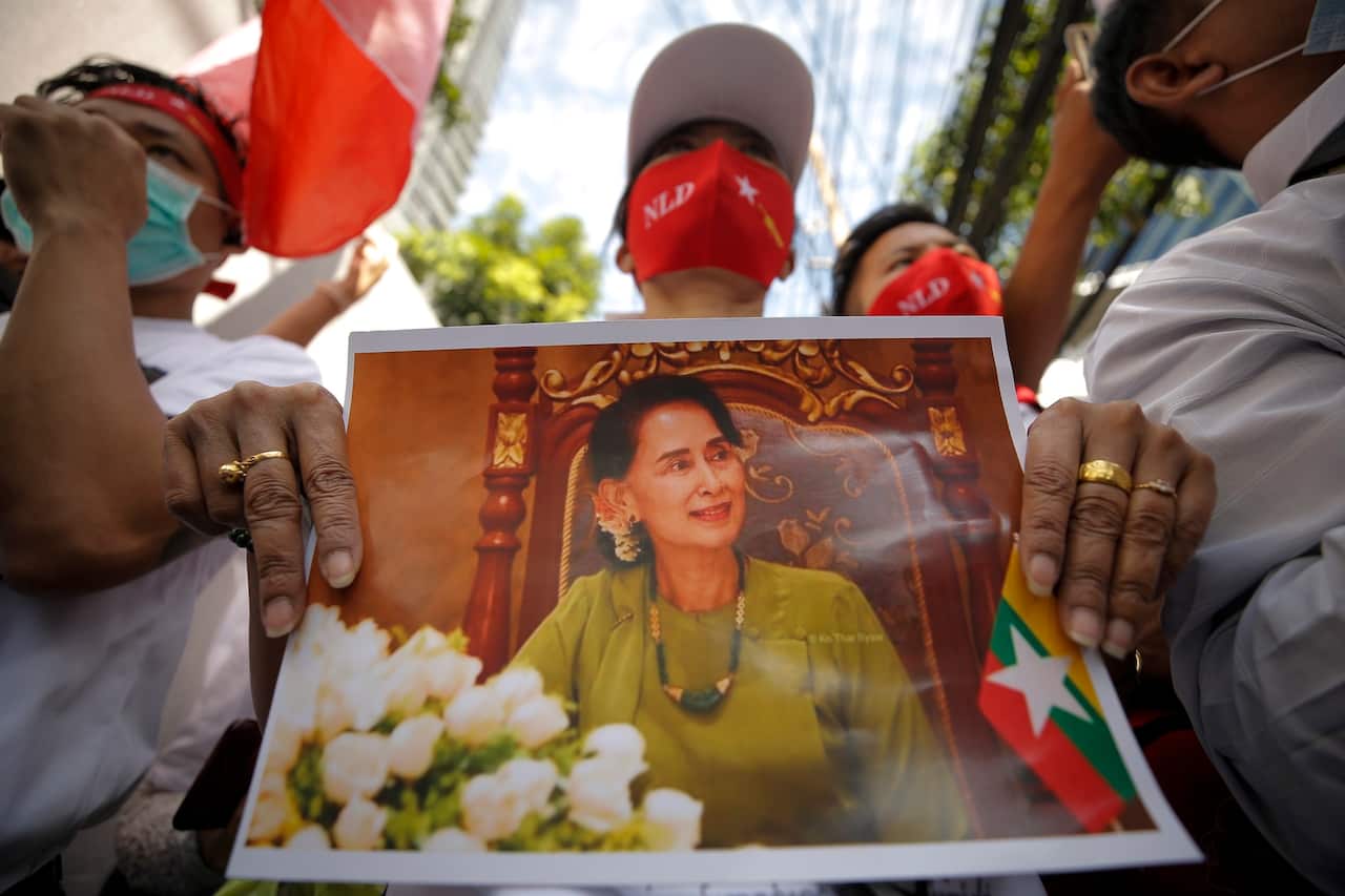 A Myanmar migrant worker living in Thailand holds a picture of Myanmar democracy icon Aung San Suu Kyi at a rally outside the Myanmar embassy in Bangkok on 19 December 2022. 