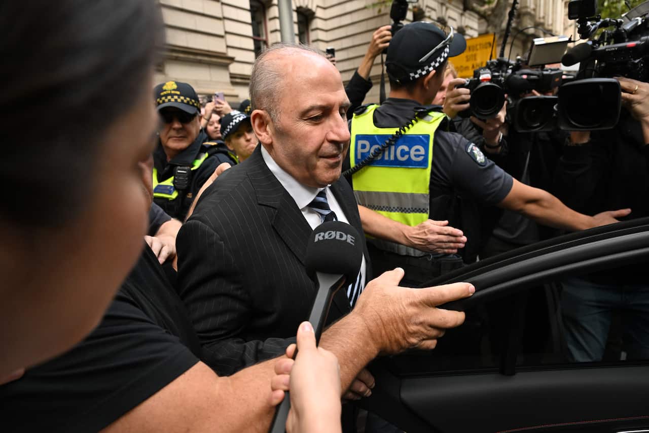 Tony Mokbel surrounded by a crowd including police and members of the media.