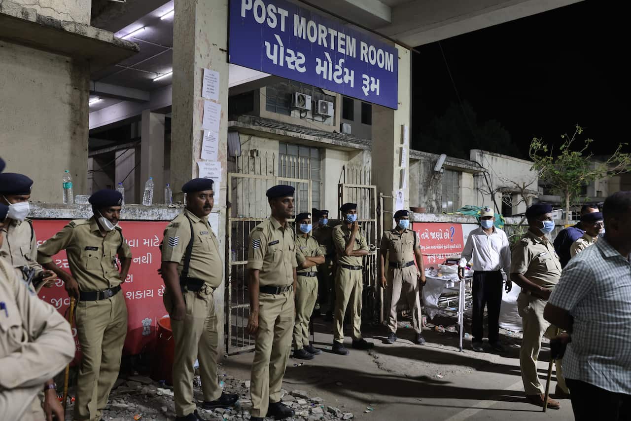 Security guards stand outside a hospital building labelled 'post mortem room'