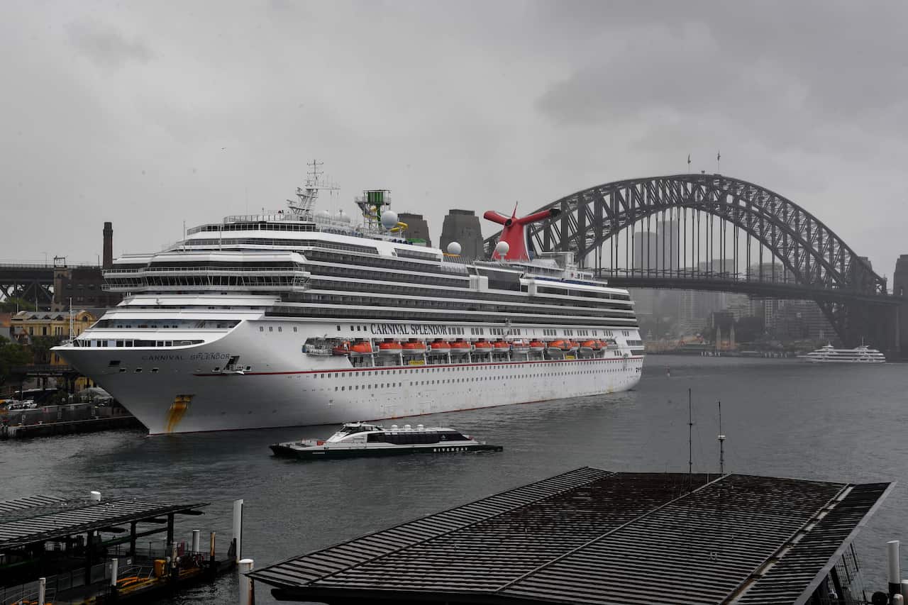 Carnival cruise ship sits in Sydney's Darling Harbour on a rainy day, with the Sydney Harbour Bridge in the background.