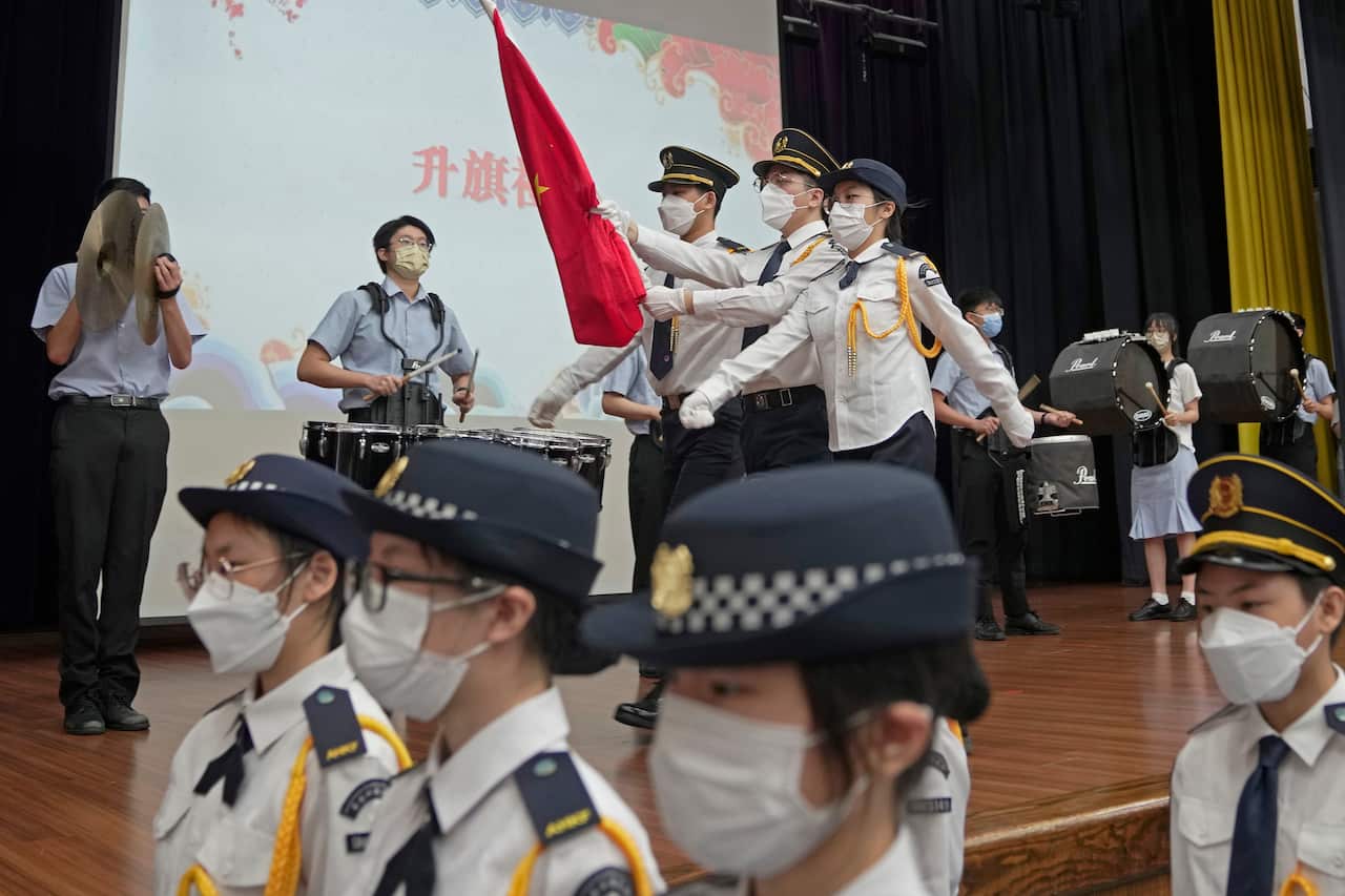A group of children, some wearing school uniforms, others wearing official attire.