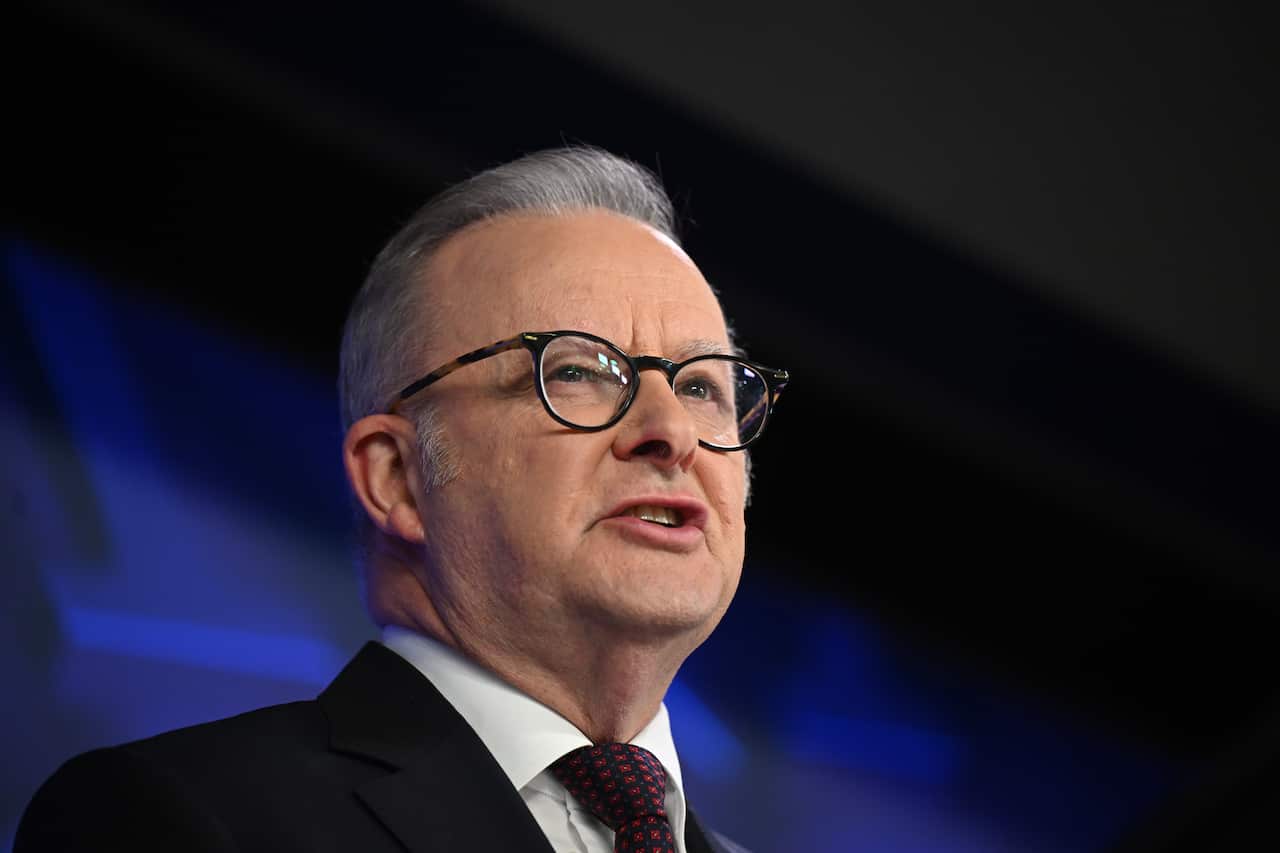 Anthony Albanese, speaking in front of a blue background.