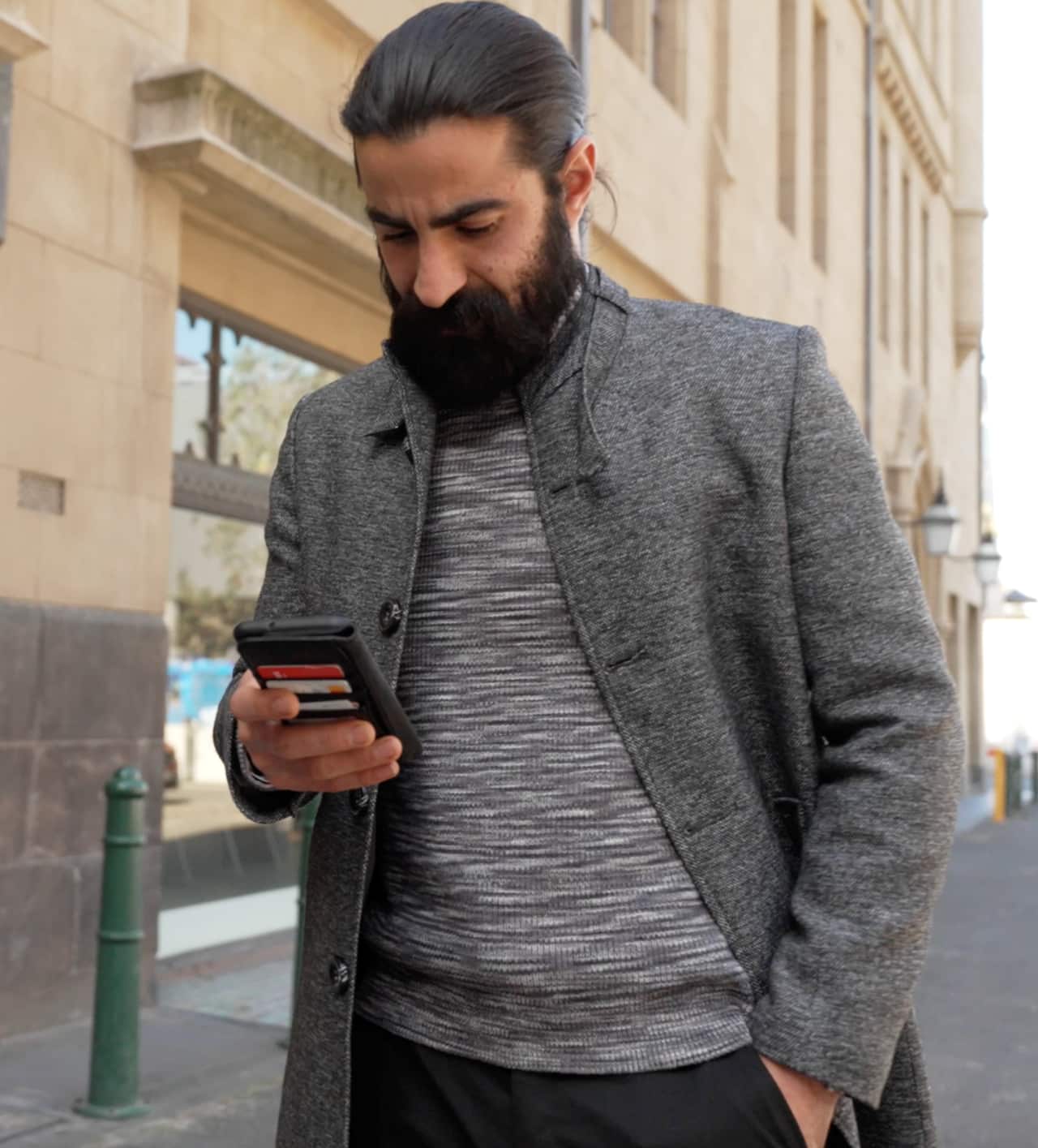 Amin looking at his phone in a city street.