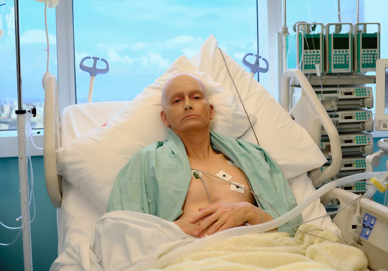 A pale, unwell bald man lies in a hospital bed, with sensors attached to his chest. 