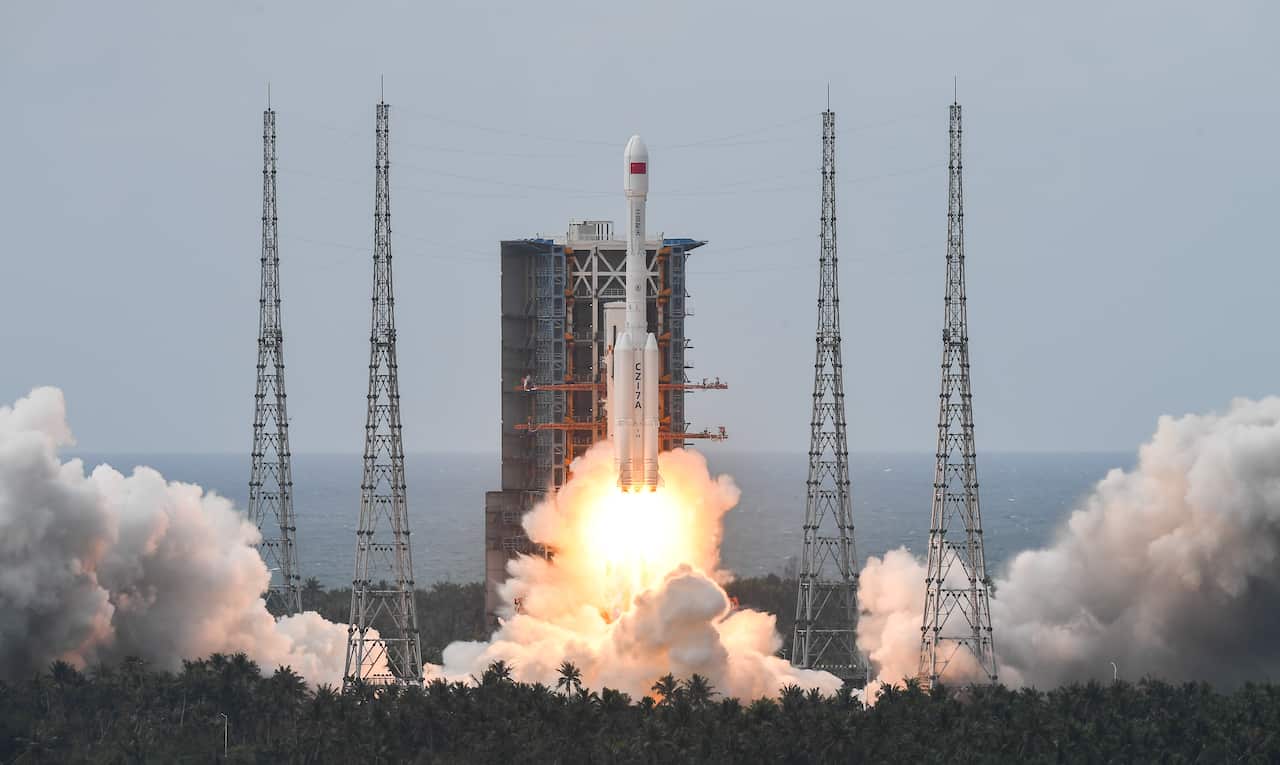 A satellite blasts off from a launch pad, releasing large amounts of fire and smoke.