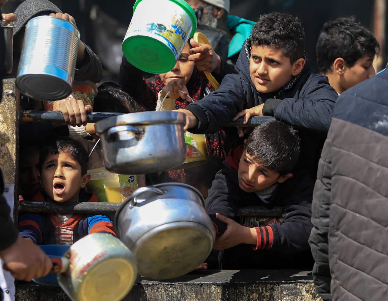 A group of children holding pots and buckets.
