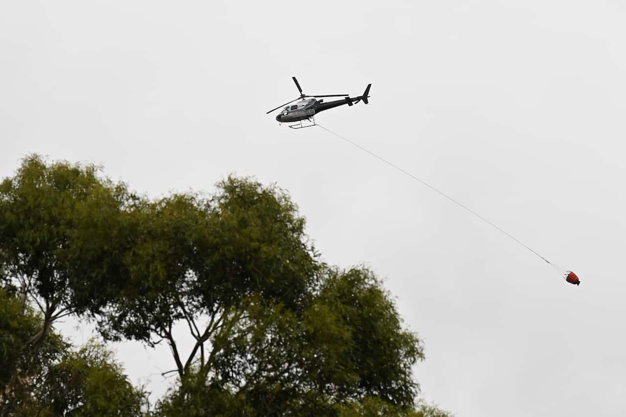 A helicopter carrying water flies overhead