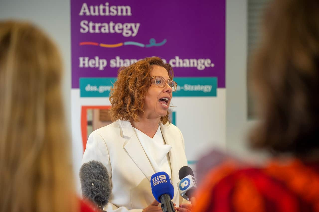 A female politician is speaking to the media, with microphones in front of her.
