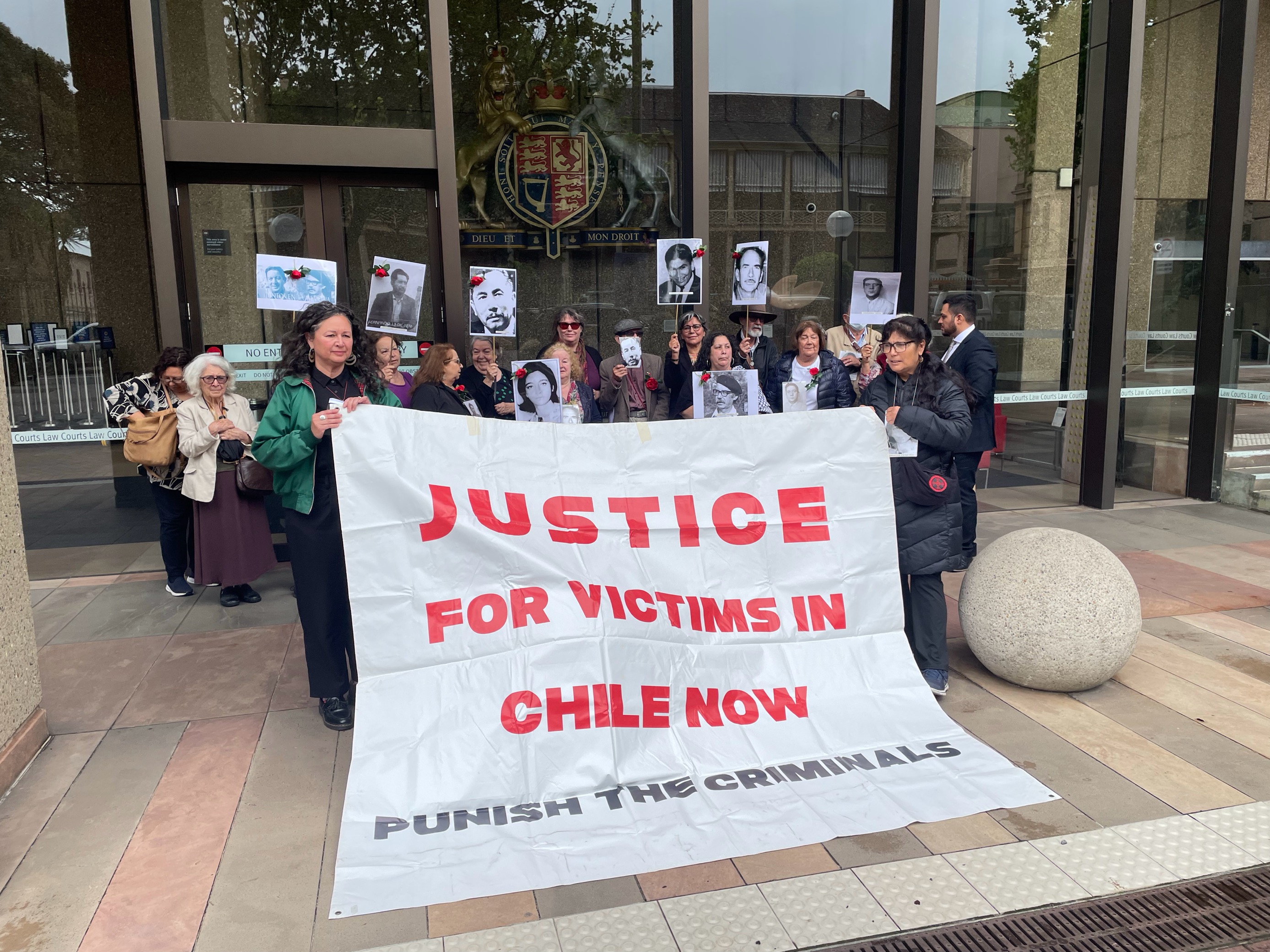 Protesters holding a banner demanding justice for victims in Chile, outside a courthouse.