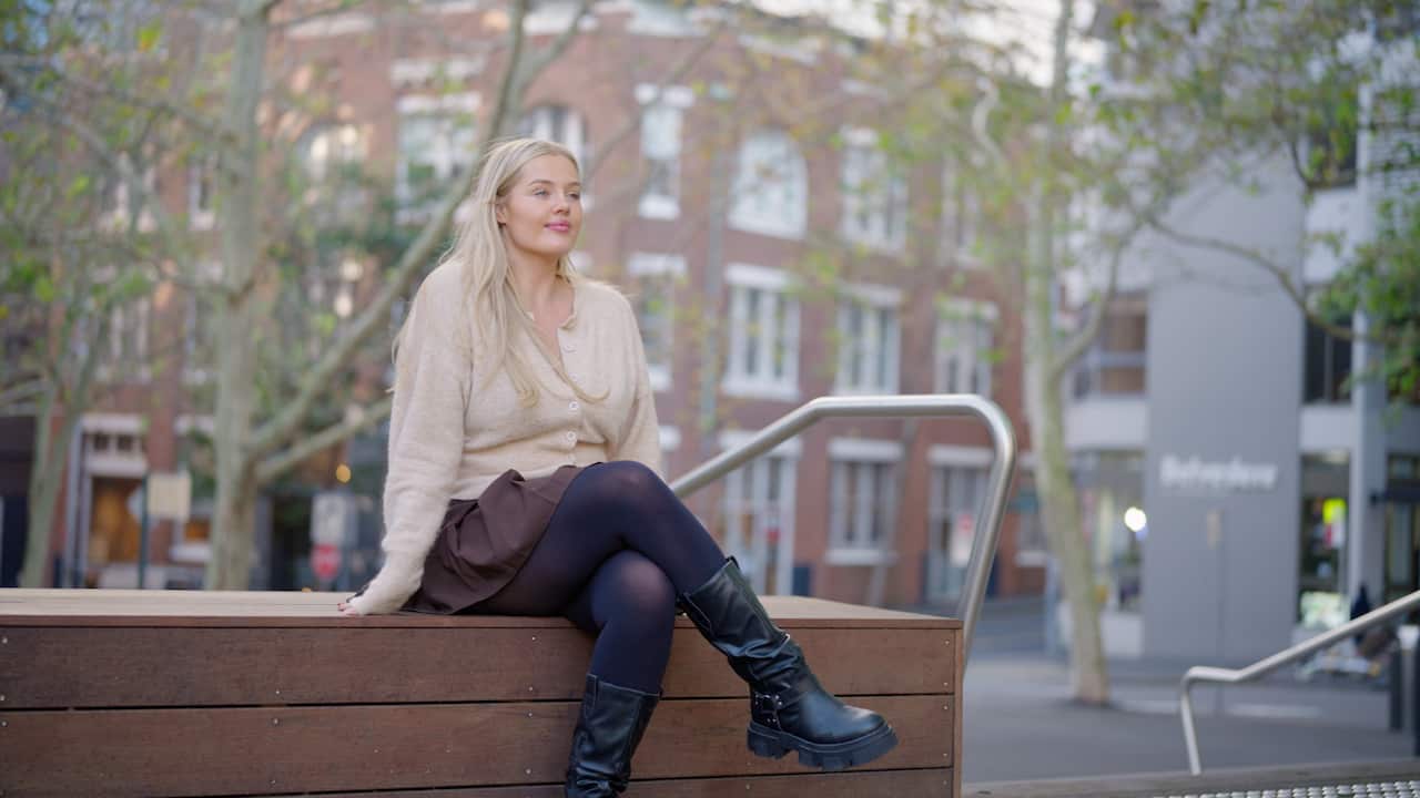 A young woman with blonde hair, sitting on a bench.