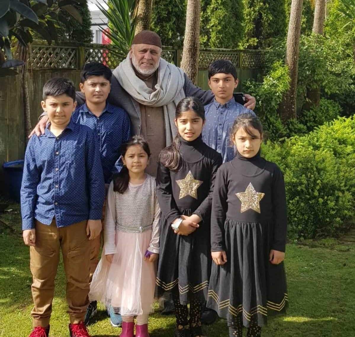 A man stands with children in a garden. 