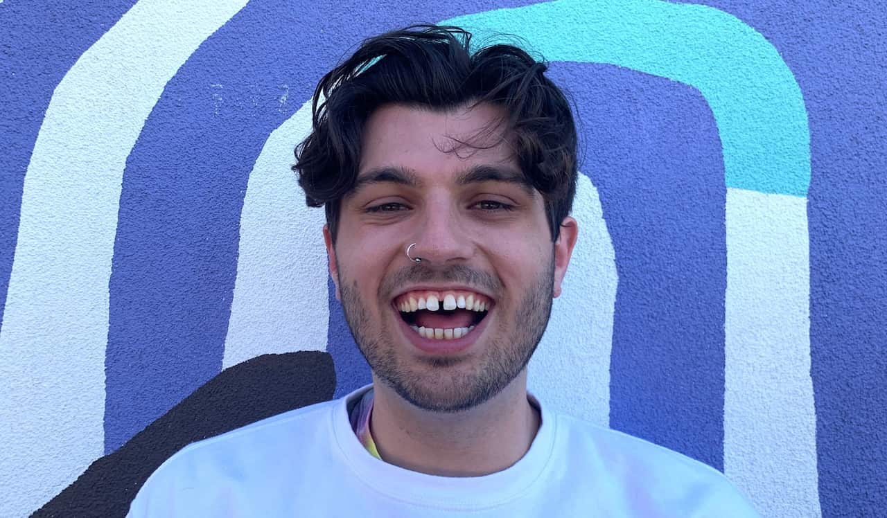 A man smiling with a white shirt looking at the camera. 