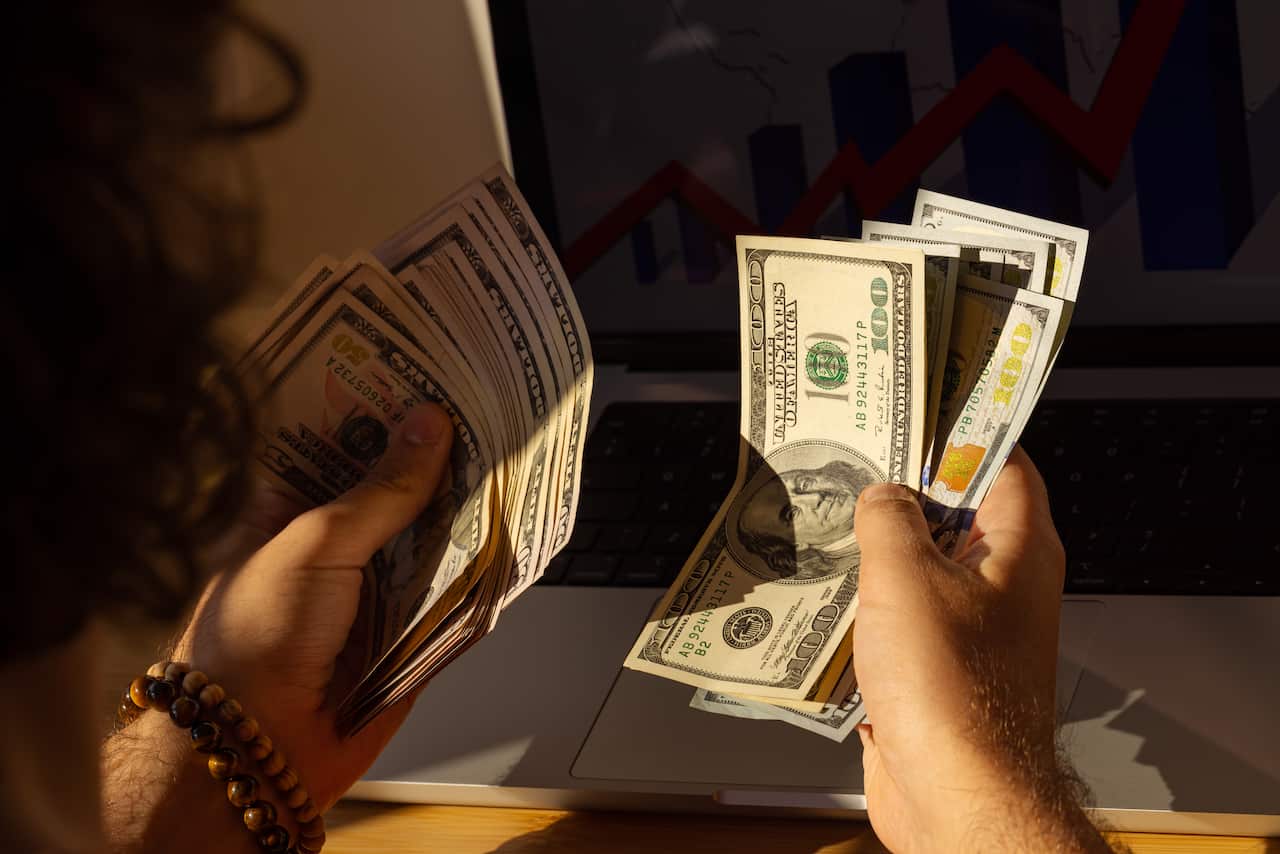 A close up of a man wearing a bracelet counting American cash 