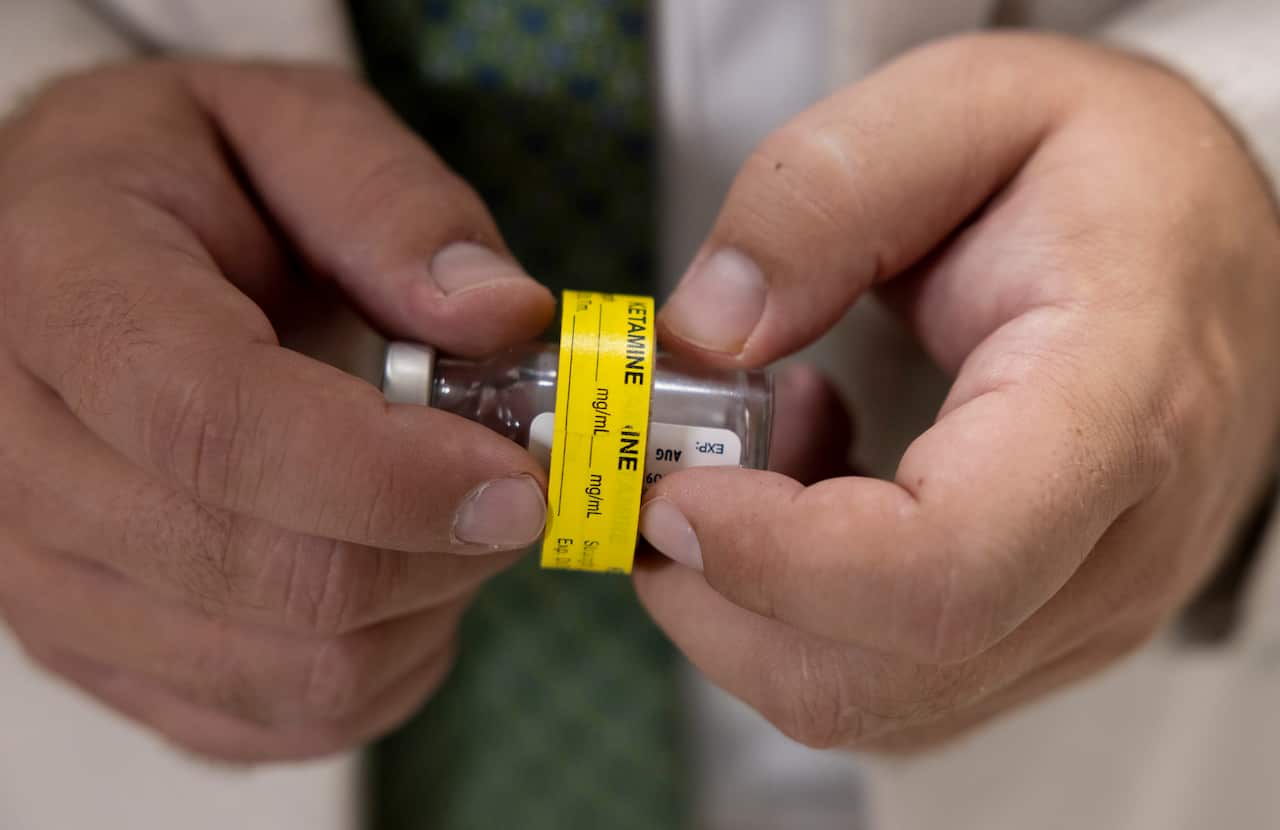 A doctor holding a vial labelled ketamine.