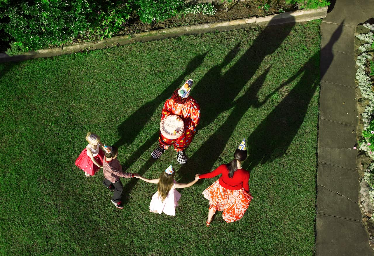 Three children and an adult with a clown on a lawn