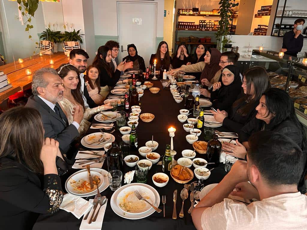 Big table of people sitting around and eating dinner.