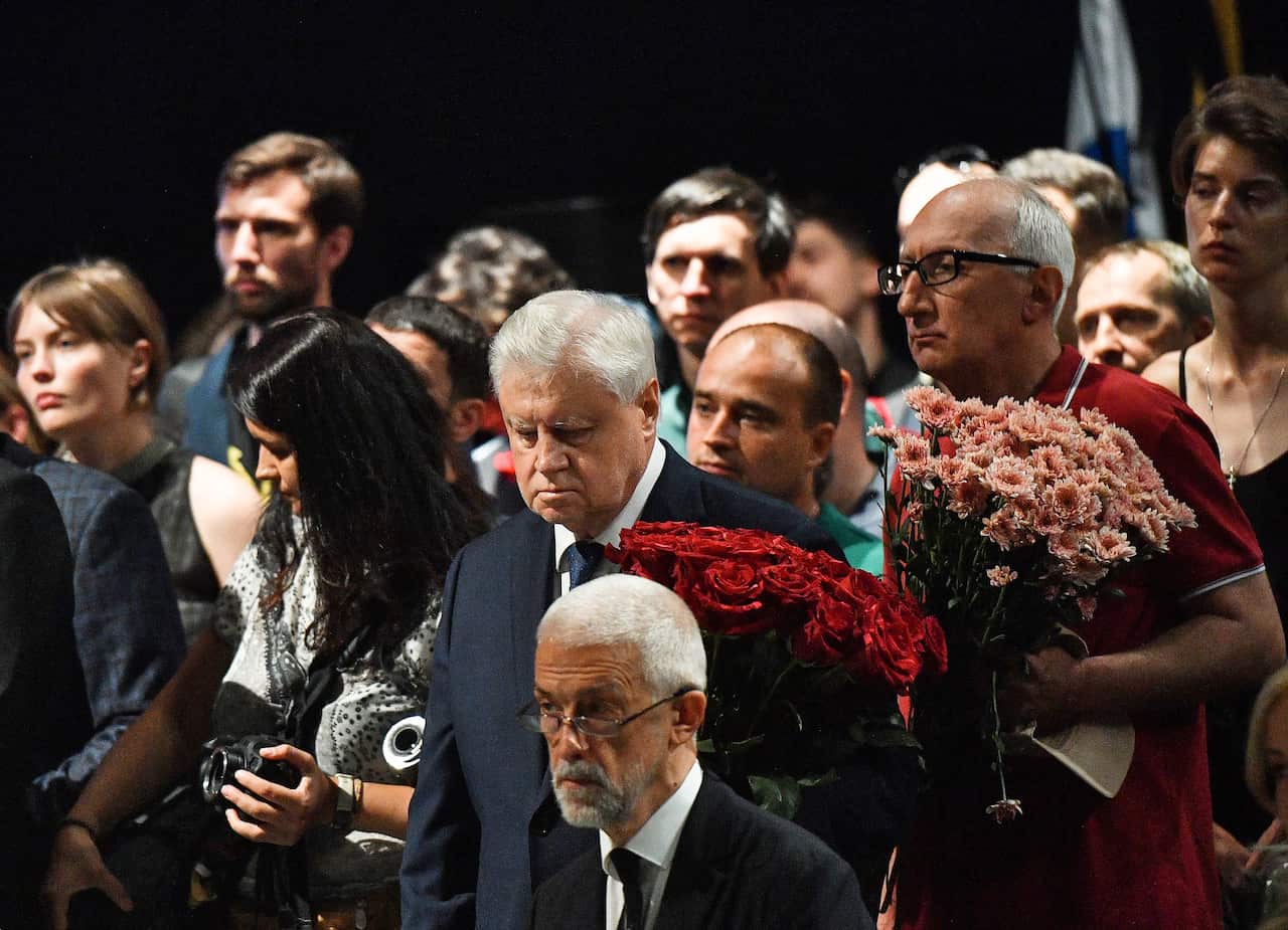 Mourners at Daria Dugina's funeral. Some are holding flowers.