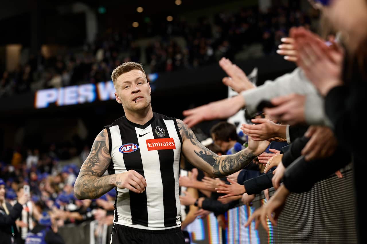 A man in a football uniform greets a crowd.