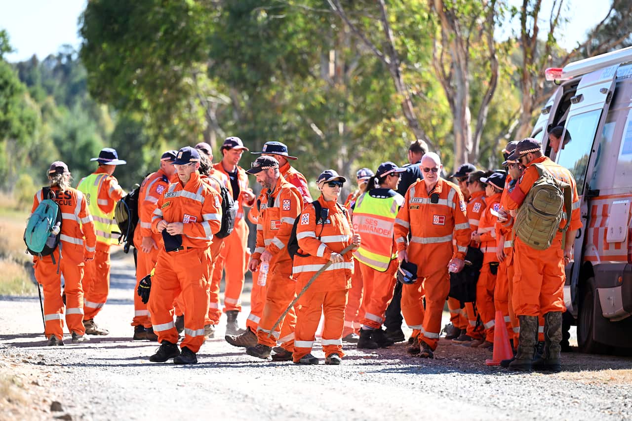A group of SES personnel in orange high-vis gear group next to a truck.