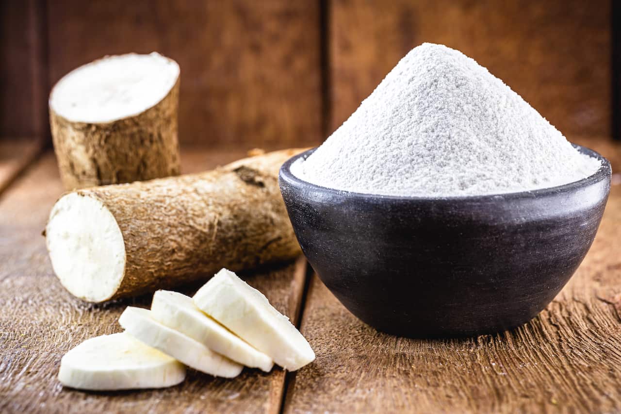 An image showing a bowl of cassava flour and the cassava root vegetable. 