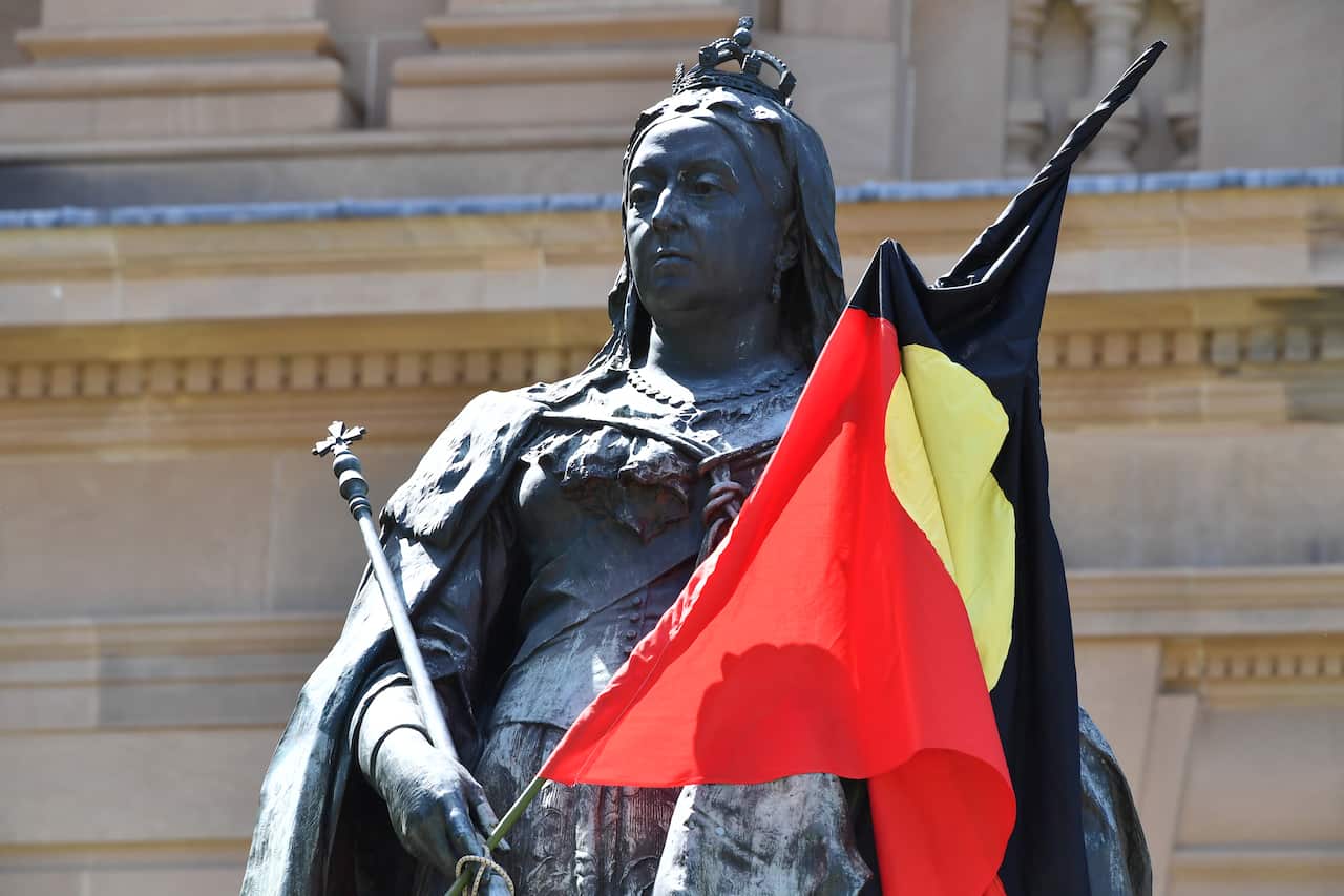 A statue of Queen Victoria with an Aboriginal flag draped over it