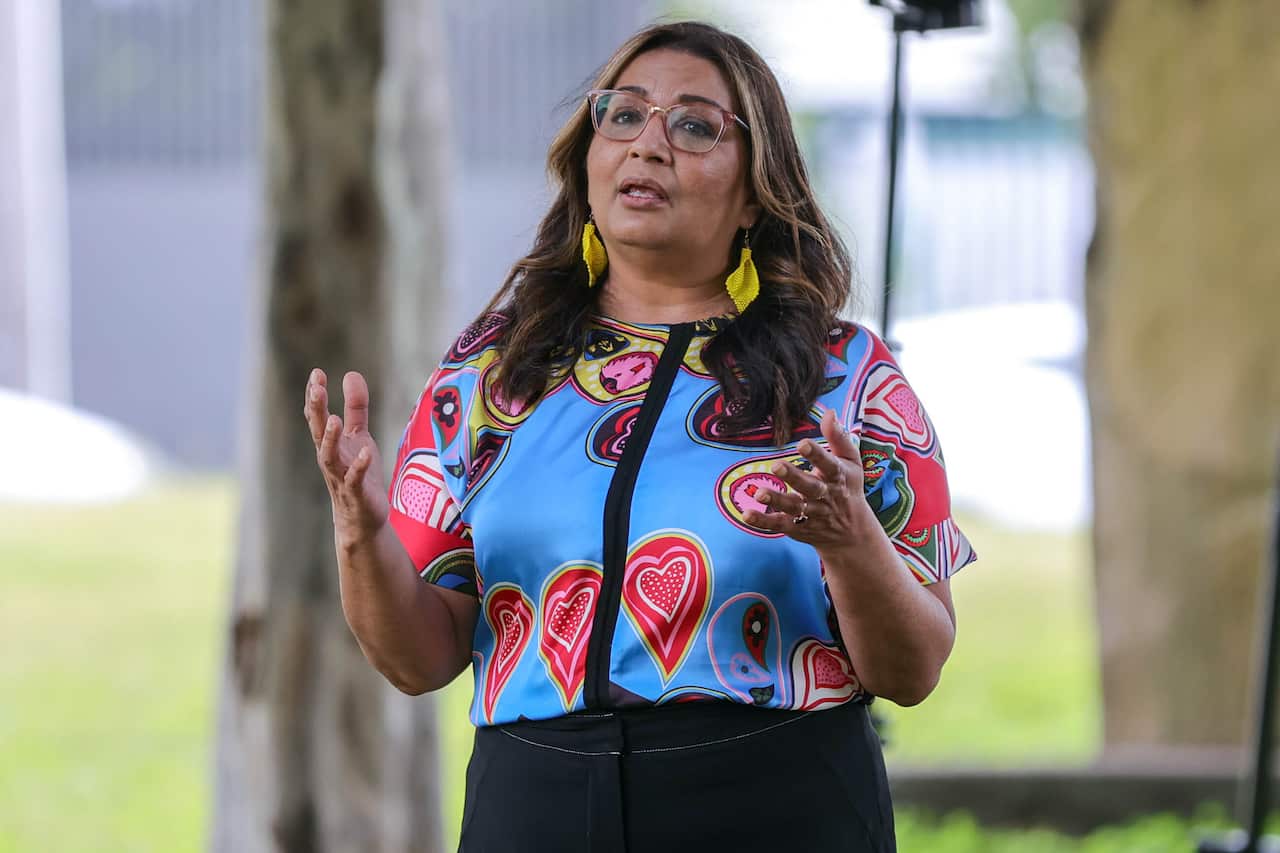 A Pakistani woman wearing a colourful shirt and bright yellow earrings