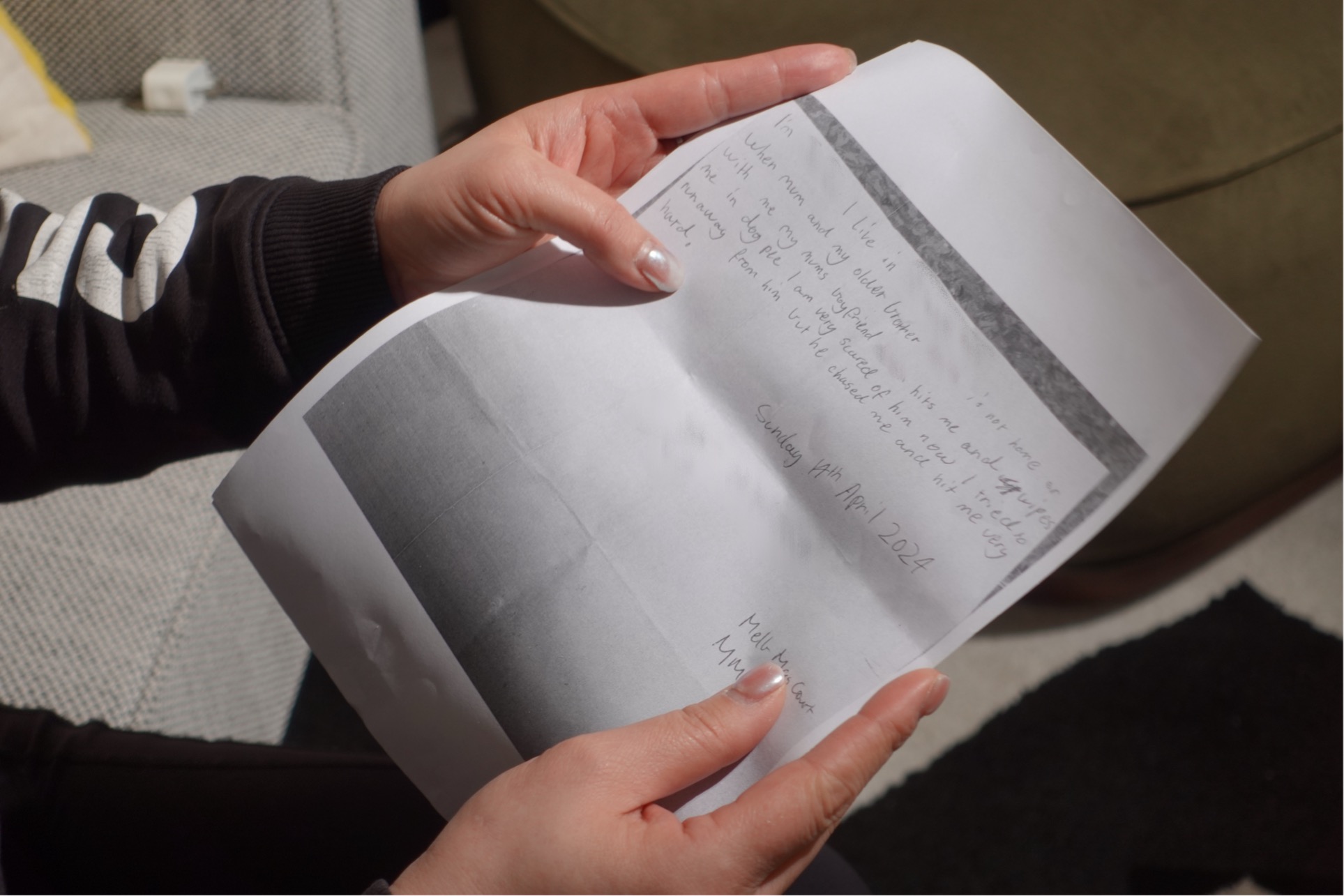 A person holds a handwritten letter with parts of the main body text blurred.