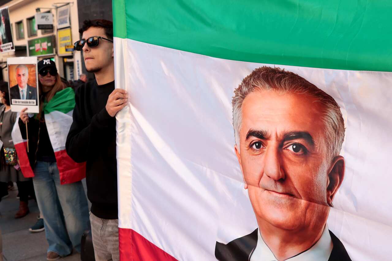 Demonstrators hold an Iranian flag with a man's face on it.