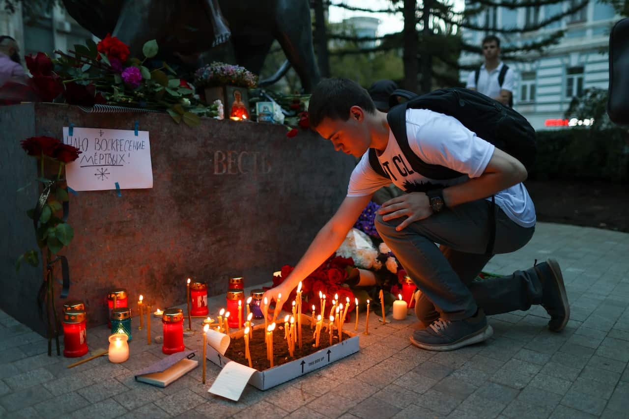 A man lights a candle at a makeshift memorial for Daria Dugina in Moscow.